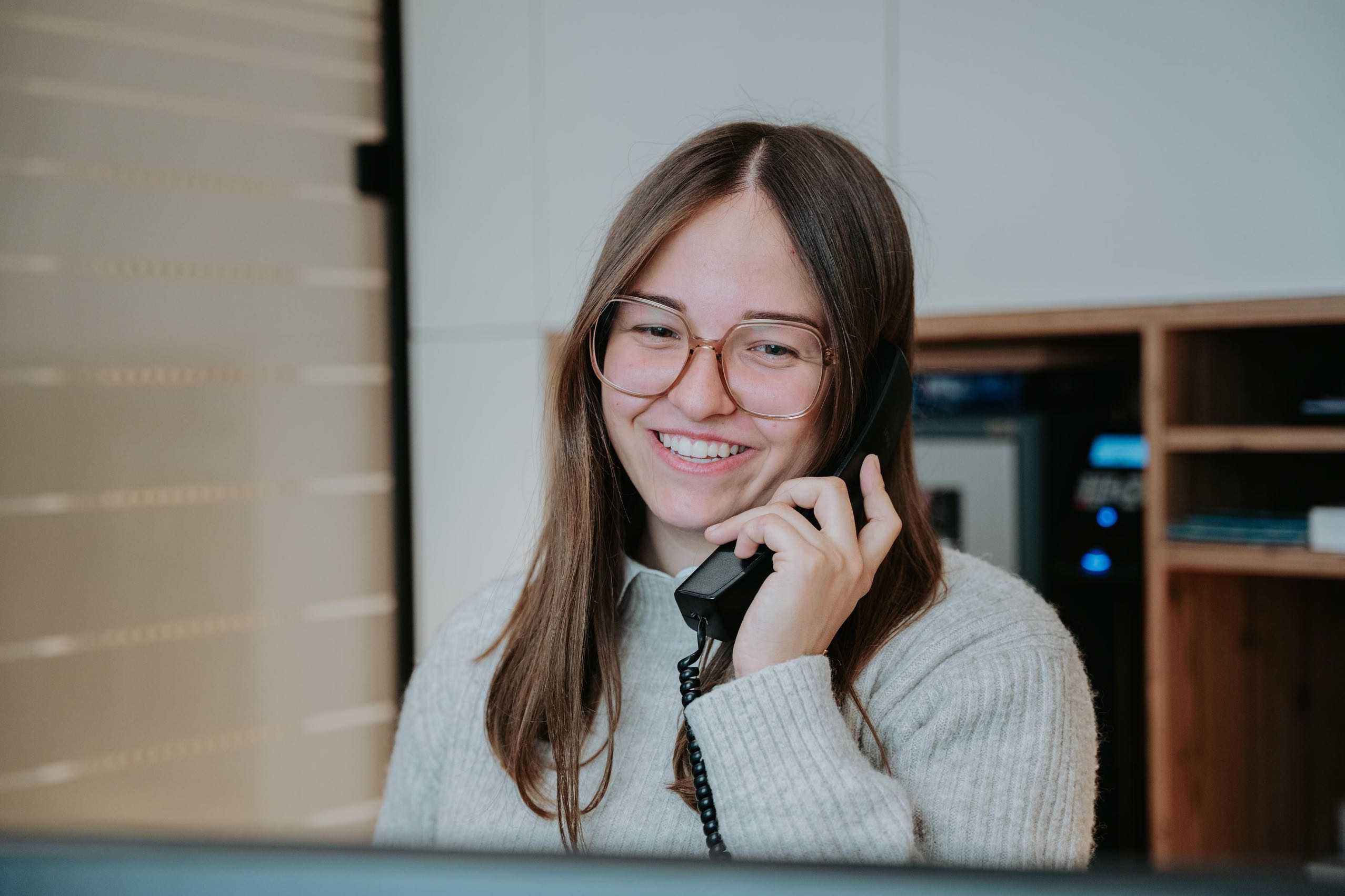 Mitarbeiterin lächelnd am Telefon.