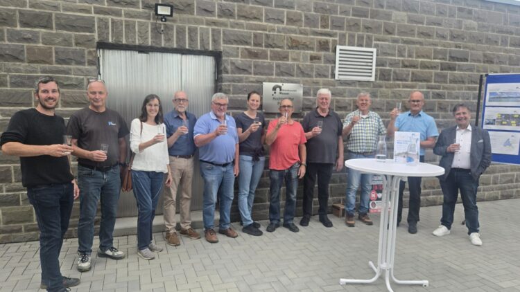 Zwölf Mitglieder des Ortsbeirats Boppard und von RheinHunsrück Wasser stehen mit Wassergläsern vor dem Hochbehälter Proffen.